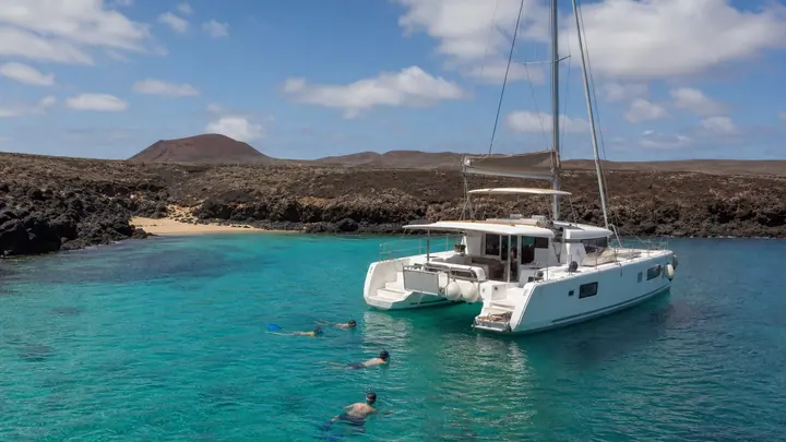 Catamaran sailing beside the volcanic coast of Isla de Lobos